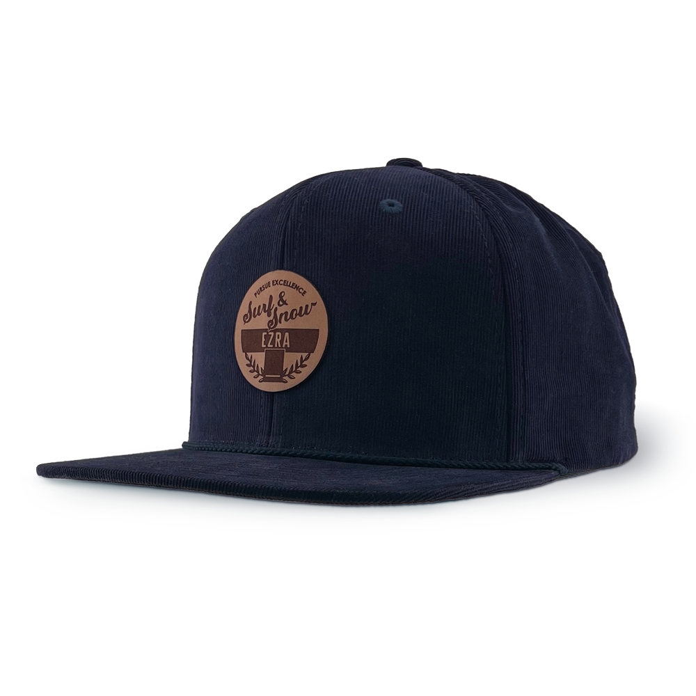Navy blue corduroy cap with a brown leather patch on a white background