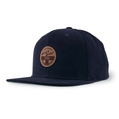 Navy blue corduroy cap with a brown leather patch on a white background