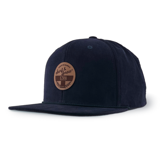 Navy blue corduroy cap with a brown leather patch on a white background