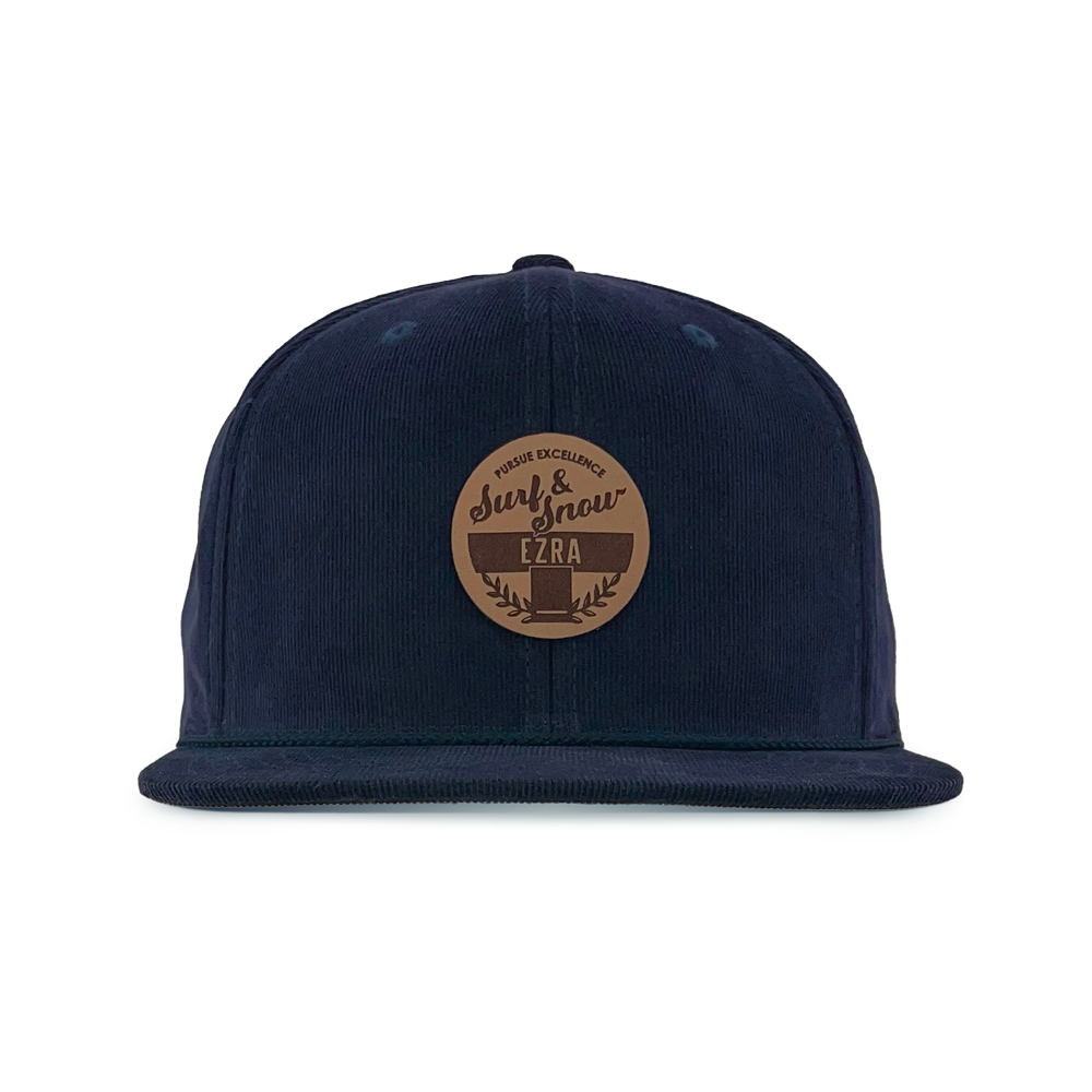Navy blue corduroy cap with a brown leather patch on a white background
