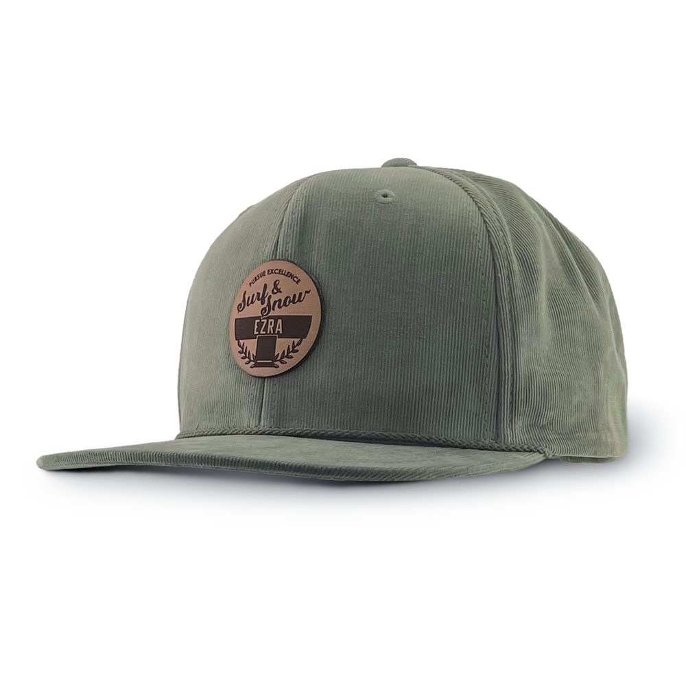 Olive green corduroy cap with a brown leather patch on a white background