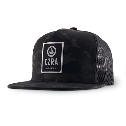 Black camouflage trucker hat with 'EZRA' logo patch on a white background