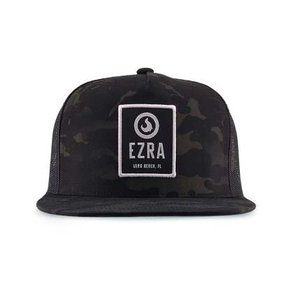 Black camouflage trucker hat with 'EZRA' logo patch on a white background
