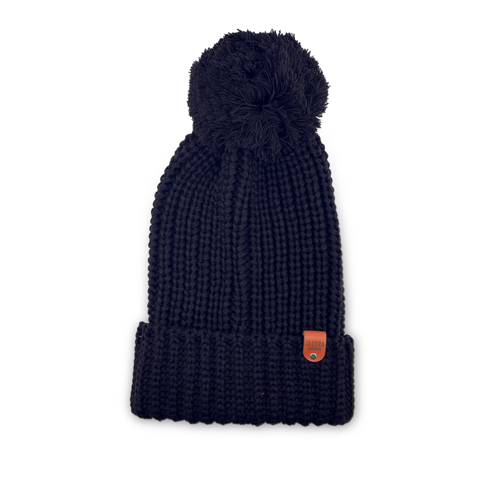 Black color knitted beanie toque with a pom-pom on a white background