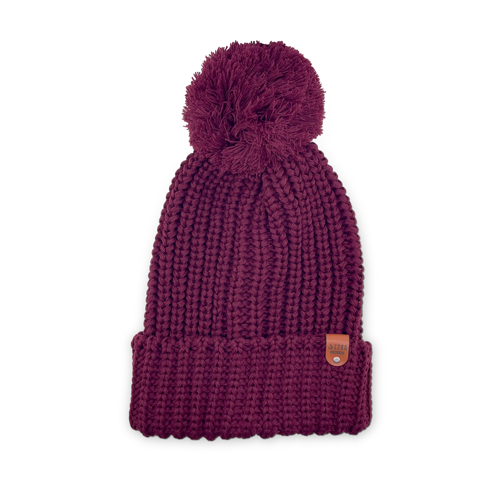 Burgundy color knitted beanie toque with a pom-pom on a white background