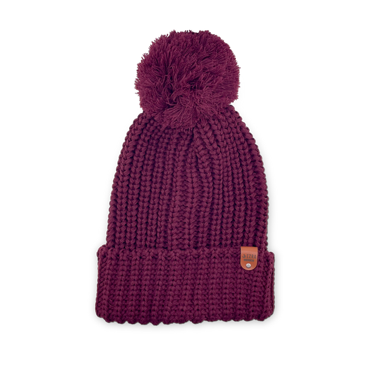 Burgundy color knitted beanie toque with a pom-pom on a white background