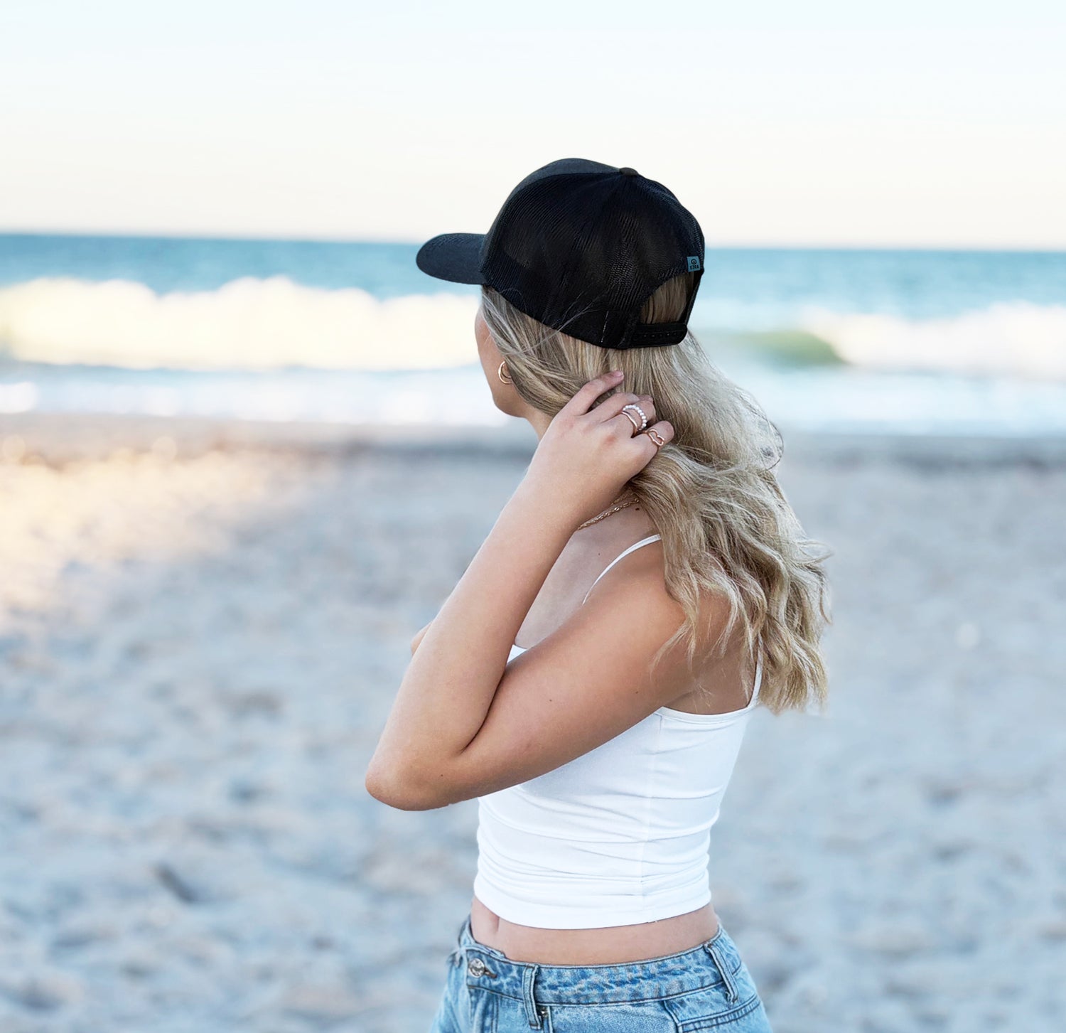 Woman wearing a black cap and white tank top on a beach