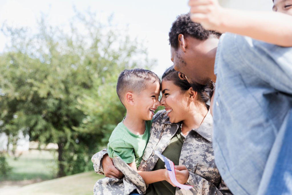Family reunion with a military member holding a child outdoors